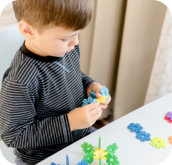 Enfant assemblant des pièces de puzzle simples sous la supervision d'une éducatrice.