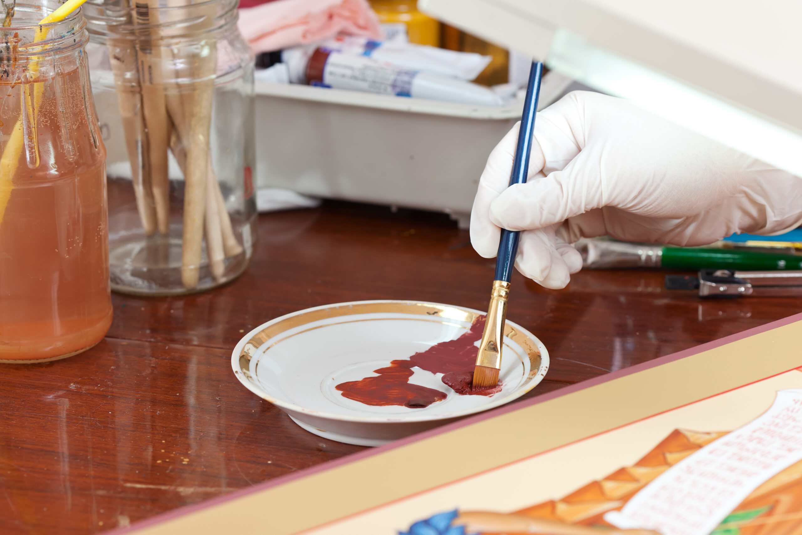 Enfant utilisant un panier trempé dans la peinture pour faire des impressions sur du papier.