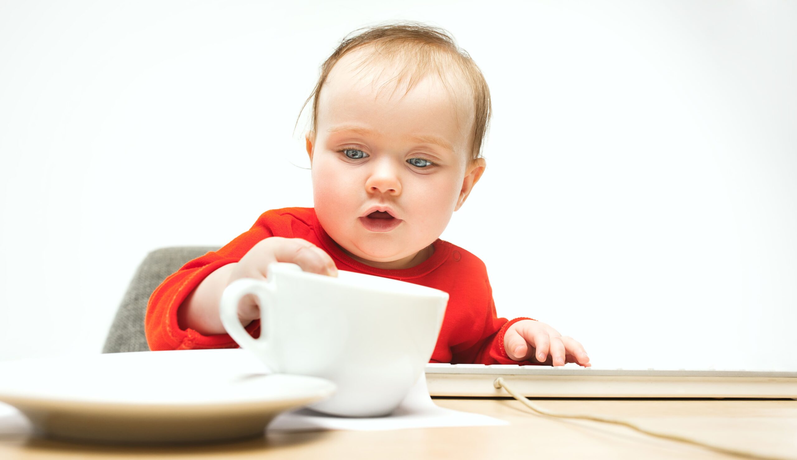 Bébé cherchant des céréales sous une tasse colorée, concentré sur le développement de ses compétences de mémoire et d'attention.